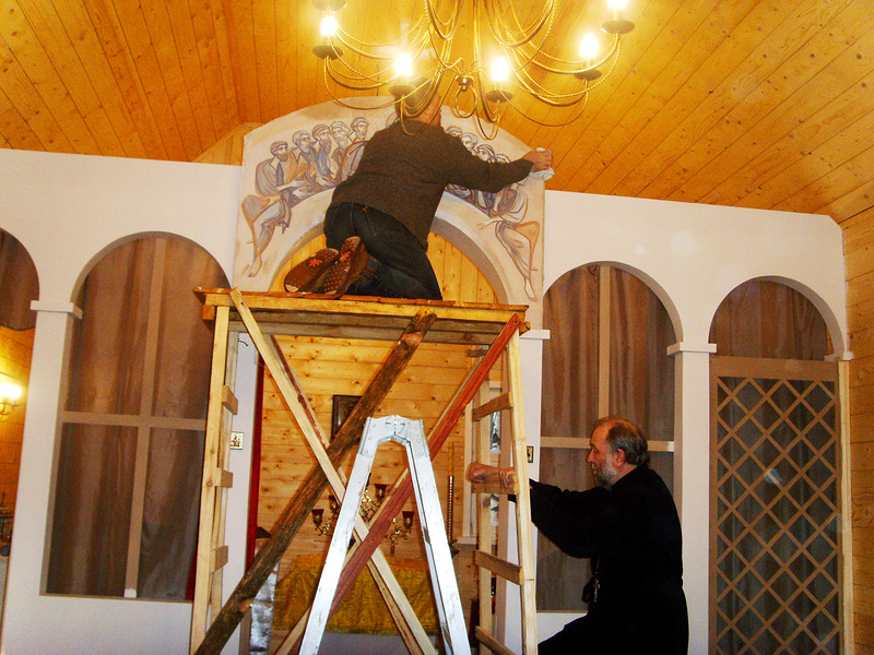 тканью художник удаляет излишки клея. отец Владислав держит сложную конструкцию